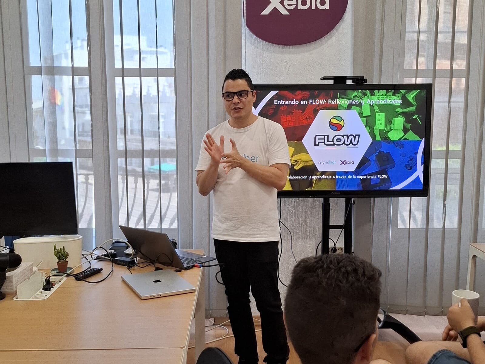 A facilitator opening the Flow debrief, the room's screen behind him reading “Entrando en FLOW: reflexiones y aprendizajes”.