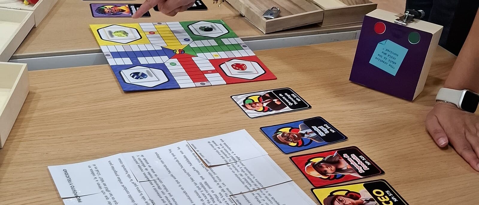 A Flow round in progress: four pairs of hands reaching across the table over an opened box, a part-solved board and a spread of clue cards.